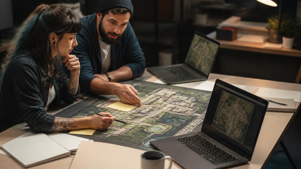 Equipe de desenvolvedores analisando mapa top-down em mesa de trabalho