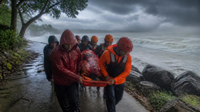 Equipe de resgate em operação sob chuva forte enquanto nuvens de tempestade se aproximam